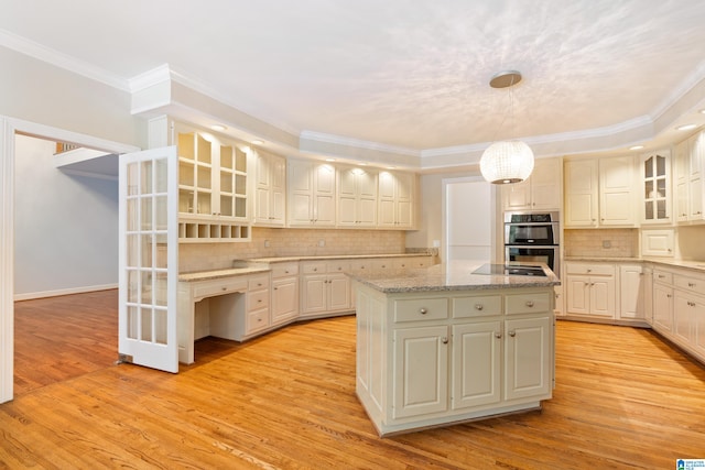 kitchen with a kitchen island, ornamental molding, light hardwood / wood-style flooring, decorative light fixtures, and double oven