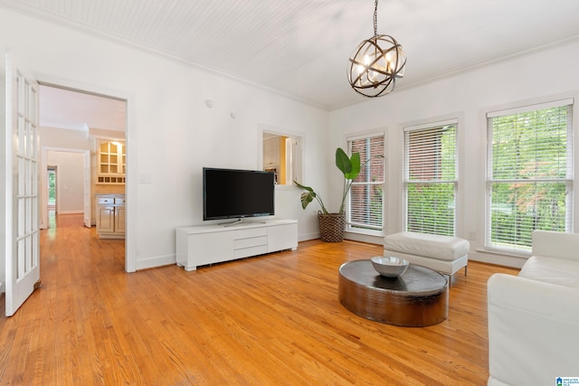 living room with light wood-type flooring, ornamental molding, and a chandelier