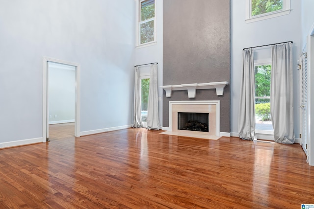 unfurnished living room featuring a high ceiling, hardwood / wood-style flooring, and plenty of natural light