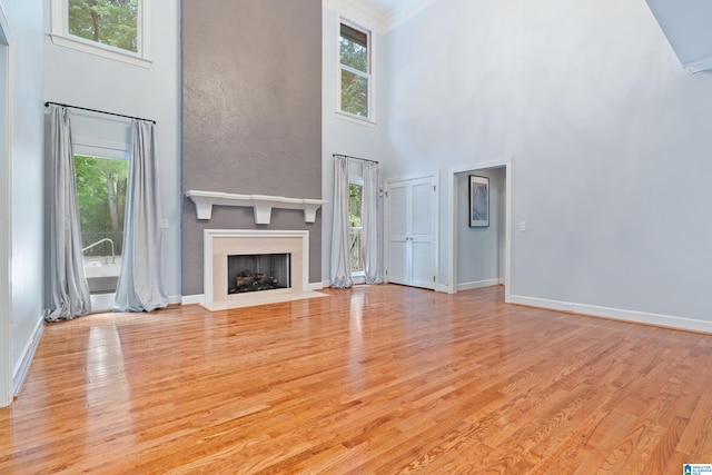 unfurnished living room with a high ceiling and light hardwood / wood-style floors