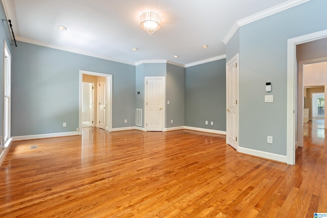 empty room with ornamental molding and light hardwood / wood-style floors