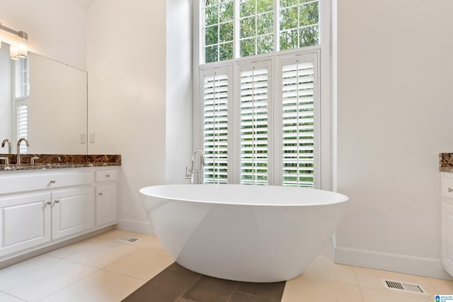 bathroom featuring a healthy amount of sunlight, a tub to relax in, tile patterned flooring, and vanity