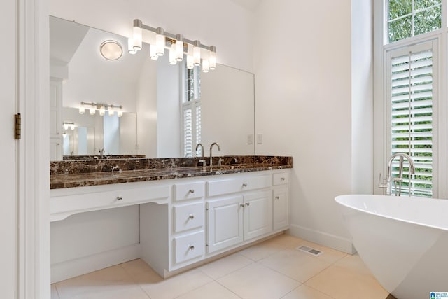 bathroom with a tub to relax in, lofted ceiling, vanity, and tile patterned floors