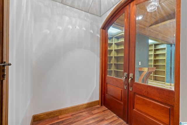 entryway with wood-type flooring, an inviting chandelier, and french doors