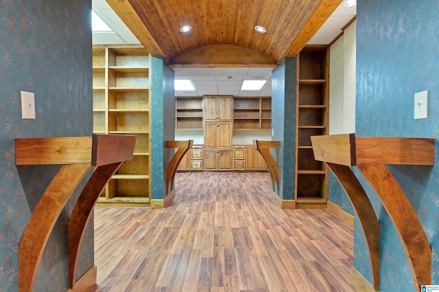 interior space with lofted ceiling, built in shelves, and hardwood / wood-style flooring