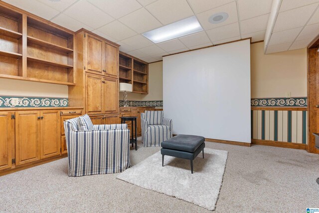 sitting room featuring a drop ceiling and light colored carpet