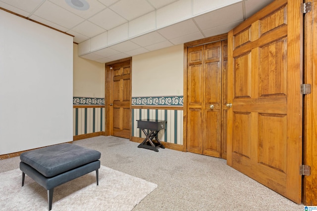 living area featuring light carpet and a drop ceiling