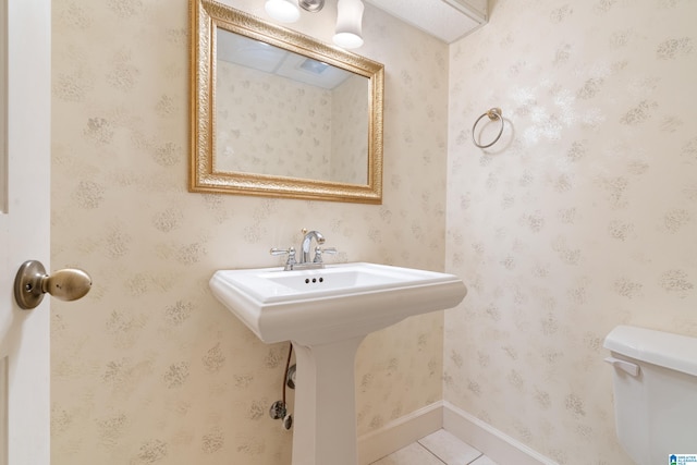 bathroom with toilet, sink, and tile patterned floors