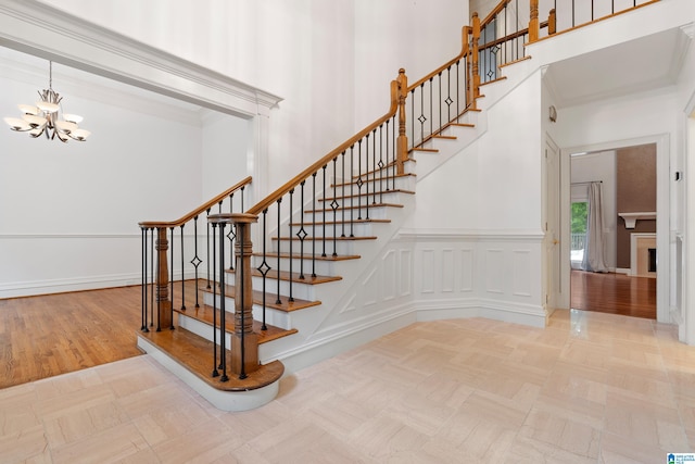 stairs featuring wood-type flooring, a high ceiling, and an inviting chandelier