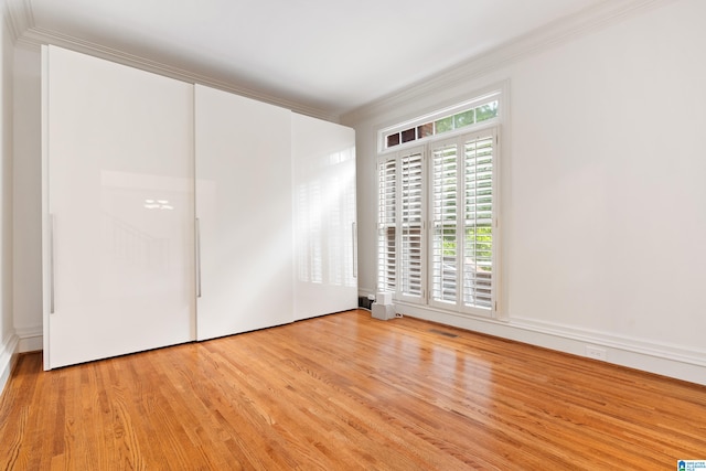 spare room with light wood-type flooring and crown molding