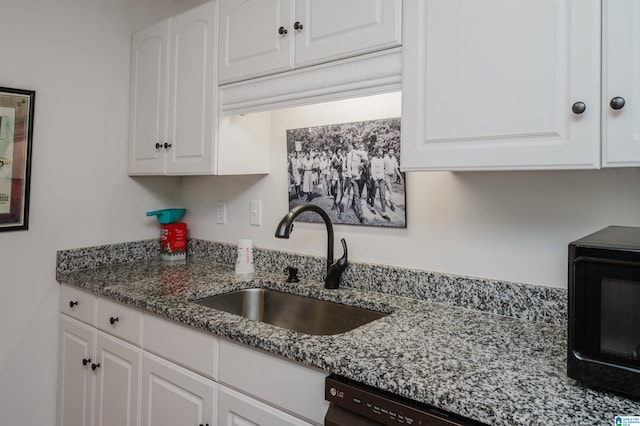 kitchen with dark stone counters, white cabinetry, black appliances, and sink