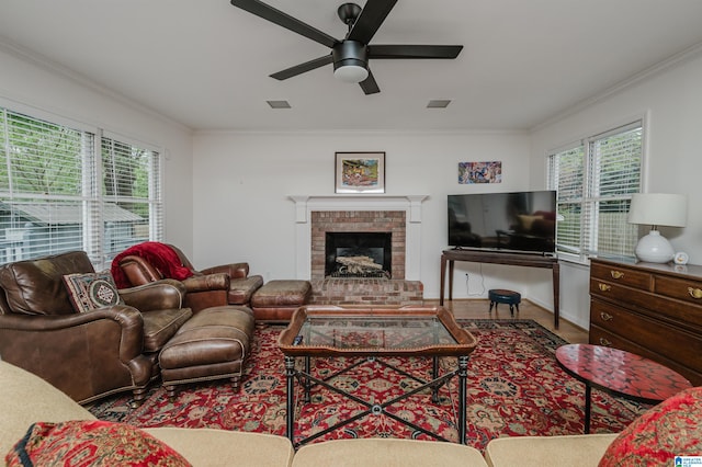 living room with crown molding, wood-type flooring, ceiling fan, and a brick fireplace