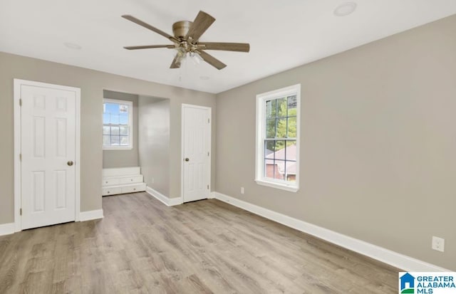 unfurnished bedroom with baseboards, wood finished floors, ceiling fan, and multiple windows