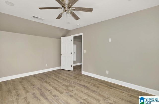 unfurnished bedroom with lofted ceiling, visible vents, wood finished floors, and baseboards