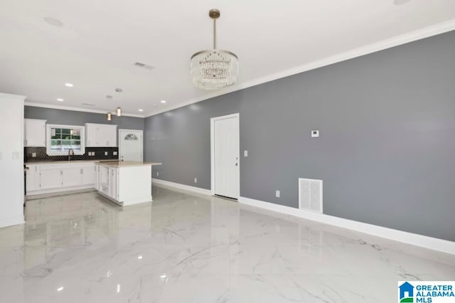 kitchen with white cabinets, a kitchen island, decorative light fixtures, a notable chandelier, and crown molding