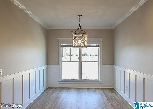 unfurnished dining area with ornamental molding, an inviting chandelier, and light hardwood / wood-style flooring