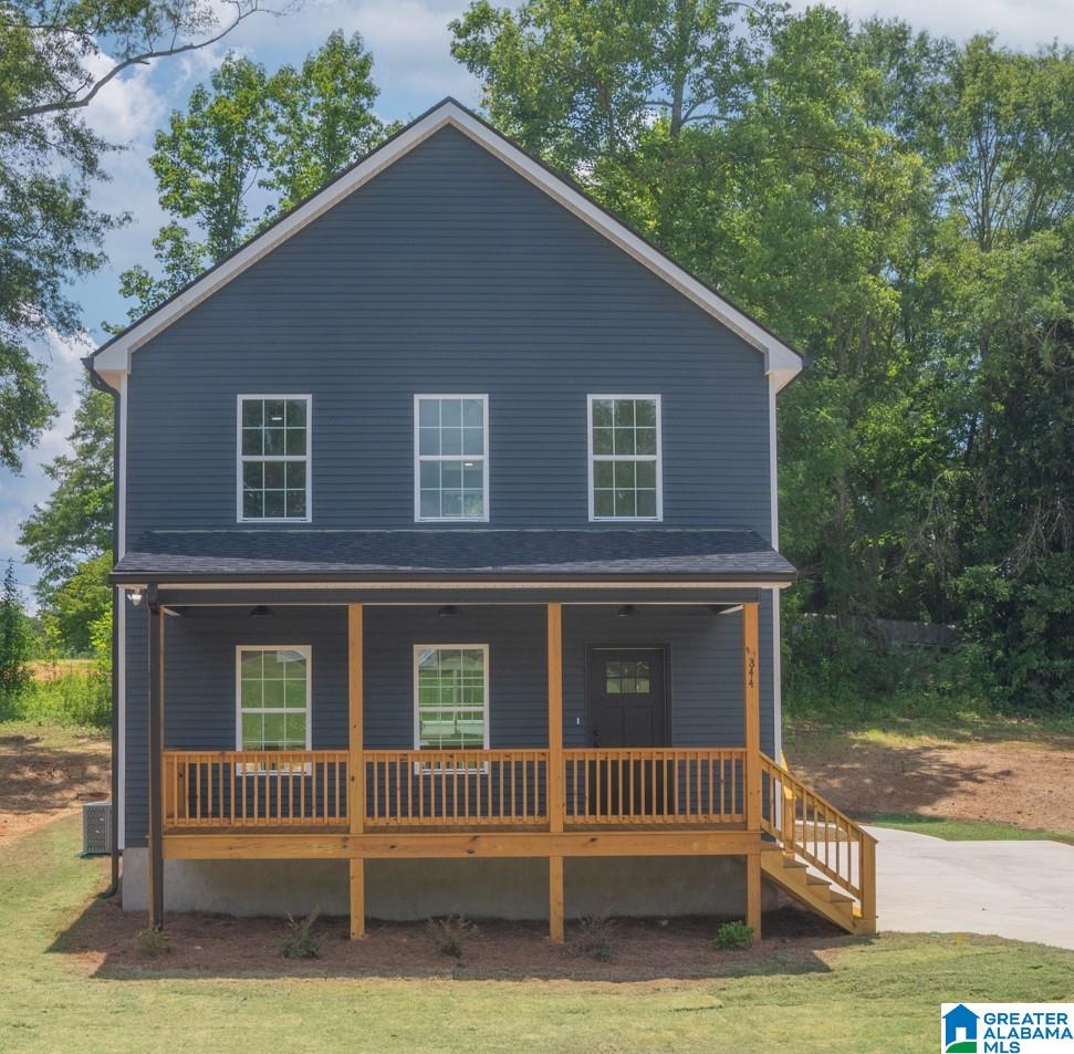 view of front facade with a front lawn, covered porch, and central air condition unit