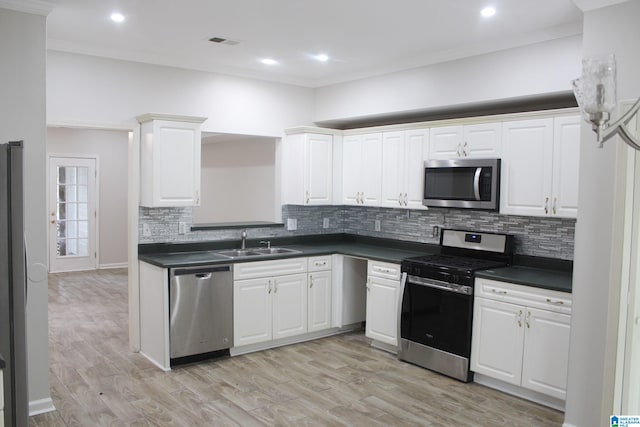 kitchen featuring white cabinets, sink, backsplash, appliances with stainless steel finishes, and light hardwood / wood-style floors