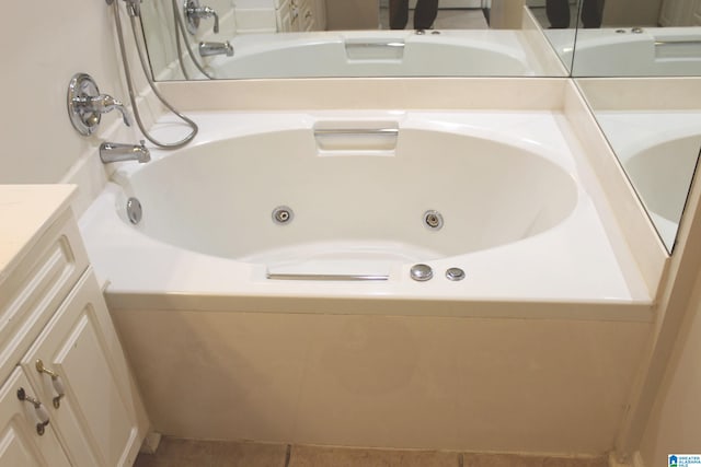 bathroom with tiled tub, vanity, and tile patterned flooring