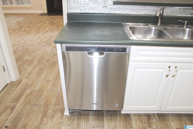 interior details with light hardwood / wood-style flooring, white cabinets, sink, and stainless steel dishwasher