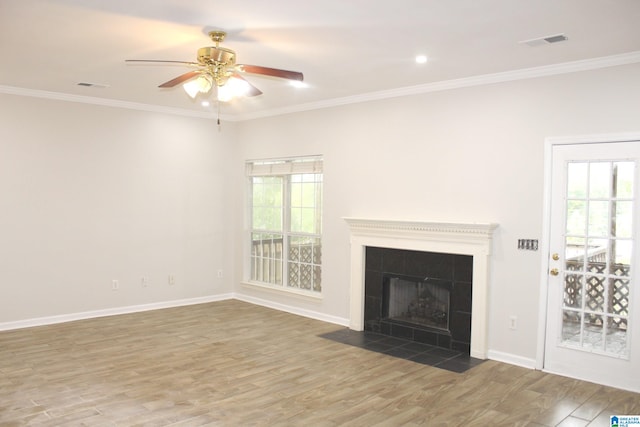 unfurnished living room with wood-type flooring, ceiling fan, a tile fireplace, and a healthy amount of sunlight