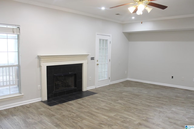 unfurnished living room featuring a tiled fireplace, ornamental molding, hardwood / wood-style floors, and ceiling fan