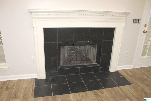 details with hardwood / wood-style flooring and a tiled fireplace