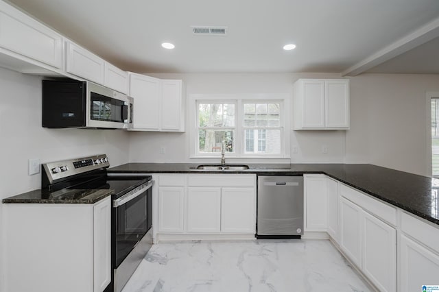 kitchen featuring appliances with stainless steel finishes, dark stone counters, sink, and white cabinets