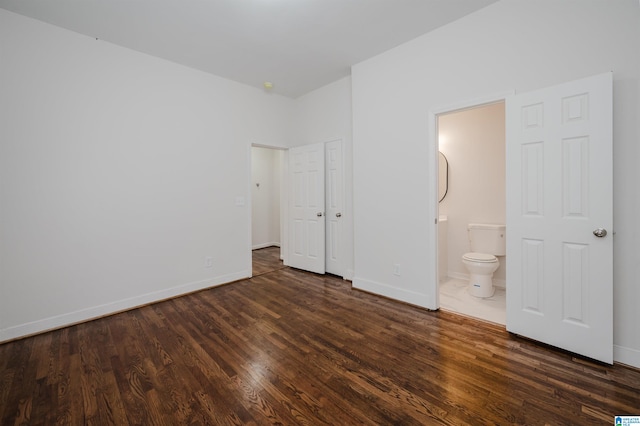 unfurnished bedroom featuring dark wood-type flooring and ensuite bathroom