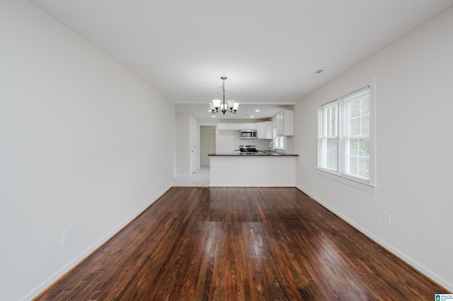 unfurnished living room with wood-type flooring, an inviting chandelier, and sink