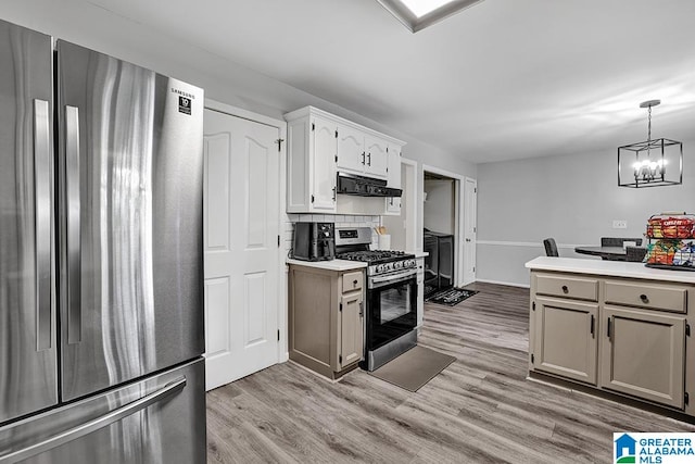 kitchen with light hardwood / wood-style floors, white cabinets, stainless steel appliances, and decorative light fixtures