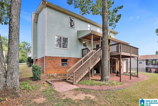 rear view of house with a wooden deck and a lawn