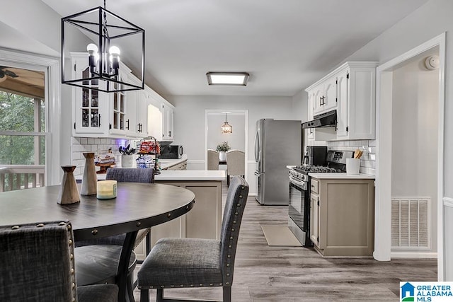 kitchen with white cabinets, appliances with stainless steel finishes, decorative backsplash, and light hardwood / wood-style flooring