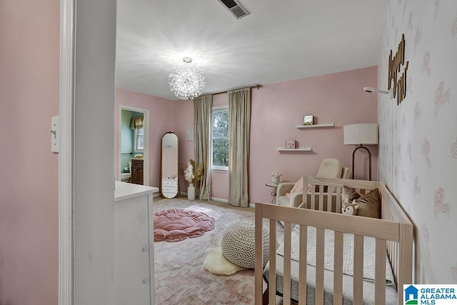 bedroom with carpet flooring, an inviting chandelier, and a nursery area