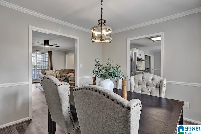 dining area with hardwood / wood-style flooring, ceiling fan with notable chandelier, and ornamental molding