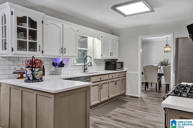 kitchen with decorative backsplash, white cabinets, appliances with stainless steel finishes, and light hardwood / wood-style flooring