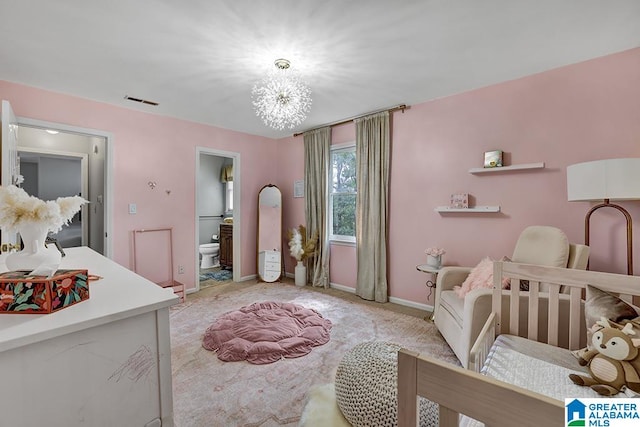 carpeted bedroom featuring a notable chandelier, connected bathroom, and a crib