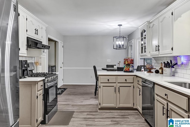 kitchen featuring appliances with stainless steel finishes, hanging light fixtures, light hardwood / wood-style floors, kitchen peninsula, and an inviting chandelier