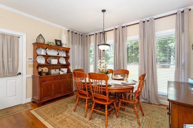 dining area with ornamental molding and light hardwood / wood-style floors