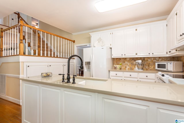 kitchen with white appliances, white cabinetry, hardwood / wood-style floors, and sink