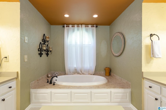 full bath with a bath, vanity, and a textured wall