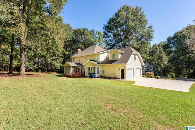 view of side of home with concrete driveway, roof with shingles, a chimney, a sunroom, and a lawn