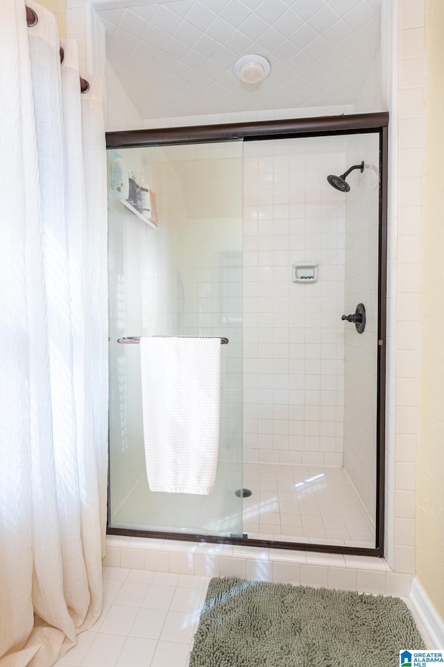 bathroom with a shower with shower door and tile patterned flooring