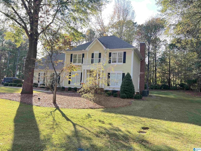 colonial home featuring a balcony, cooling unit, and a front lawn