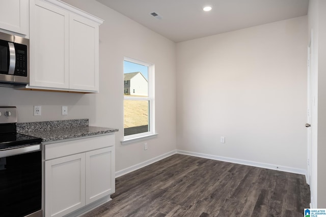 kitchen featuring dark stone countertops, stainless steel appliances, dark hardwood / wood-style floors, and white cabinets