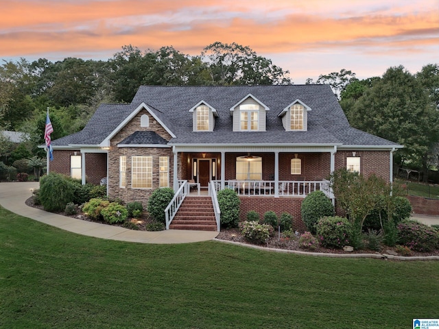 new england style home featuring a porch and a yard