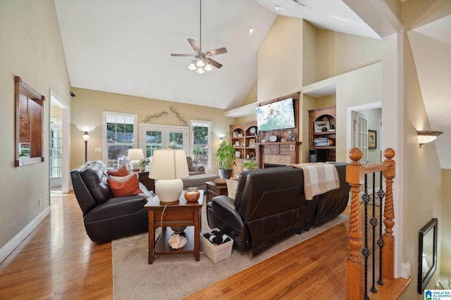 living room with light wood-type flooring, ceiling fan, and high vaulted ceiling