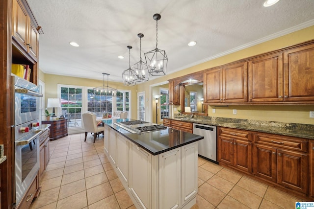 kitchen with light tile patterned floors, ornamental molding, a textured ceiling, decorative light fixtures, and appliances with stainless steel finishes