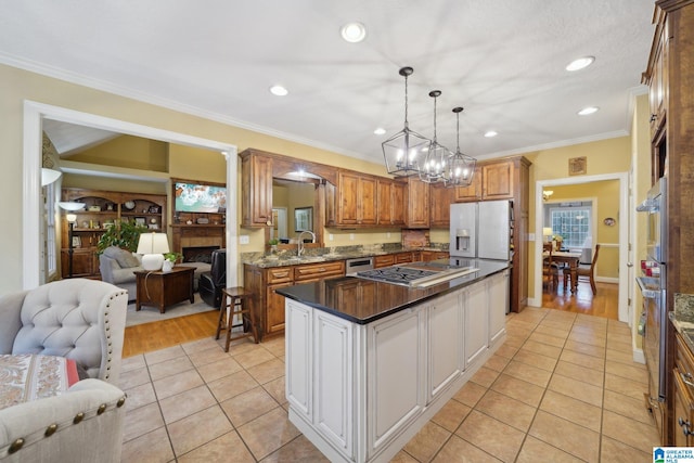 kitchen with pendant lighting, light tile patterned floors, a kitchen island, a fireplace, and crown molding