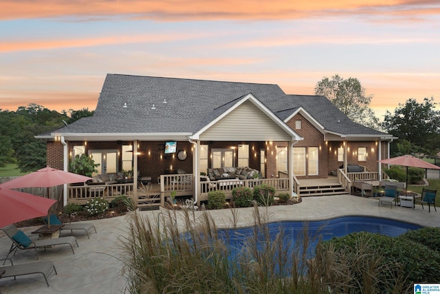 back house at dusk featuring a patio and a swimming pool side deck